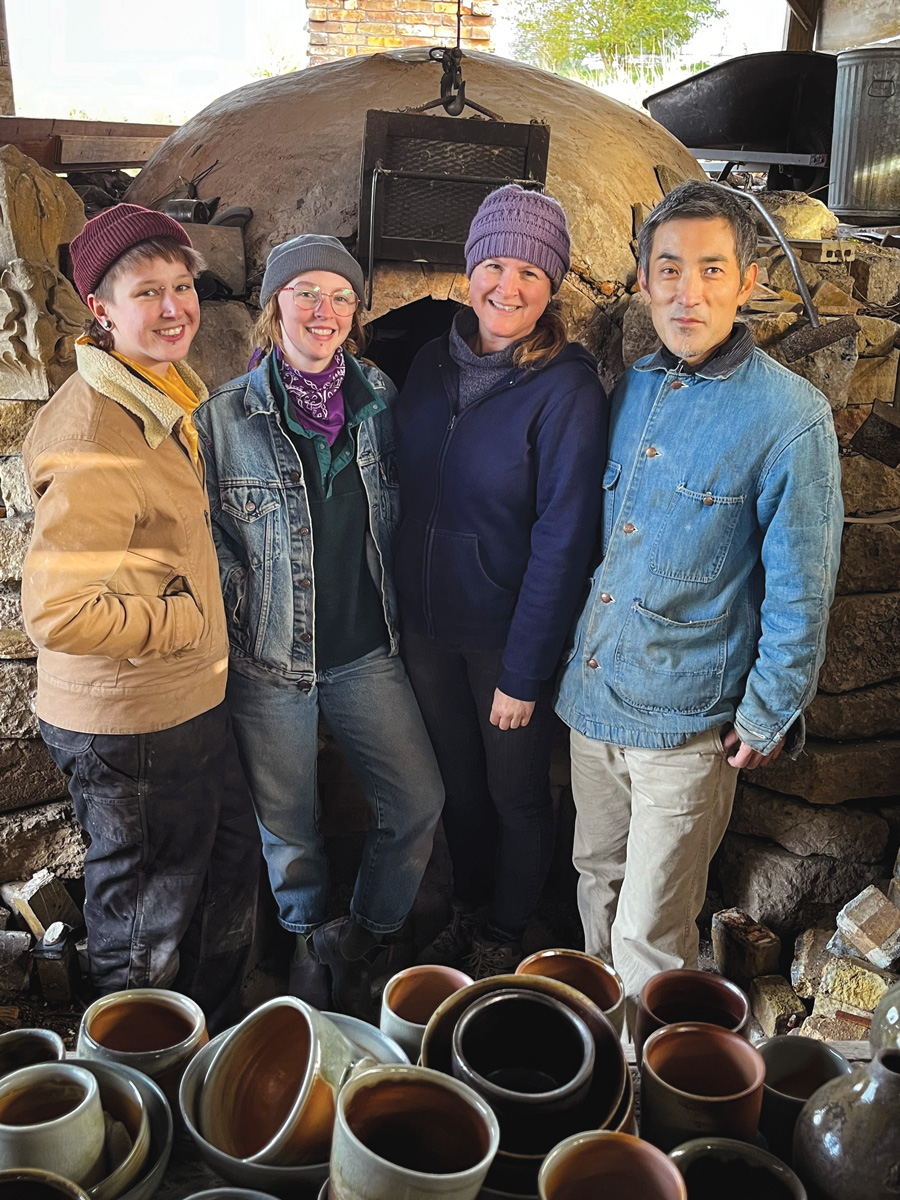 group of four standing in front of kiln smiling