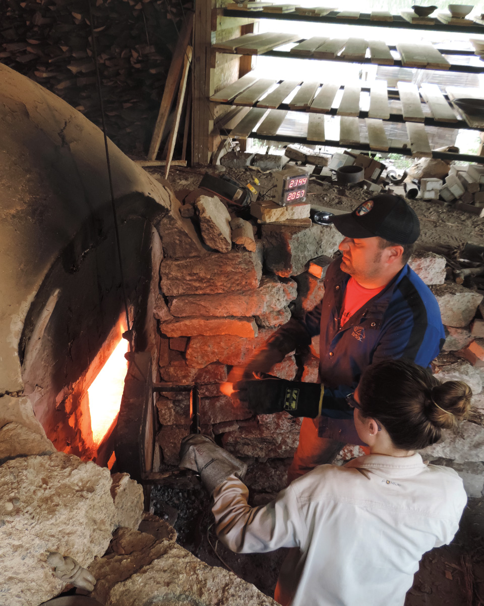 teacher and student open kiln door while firing