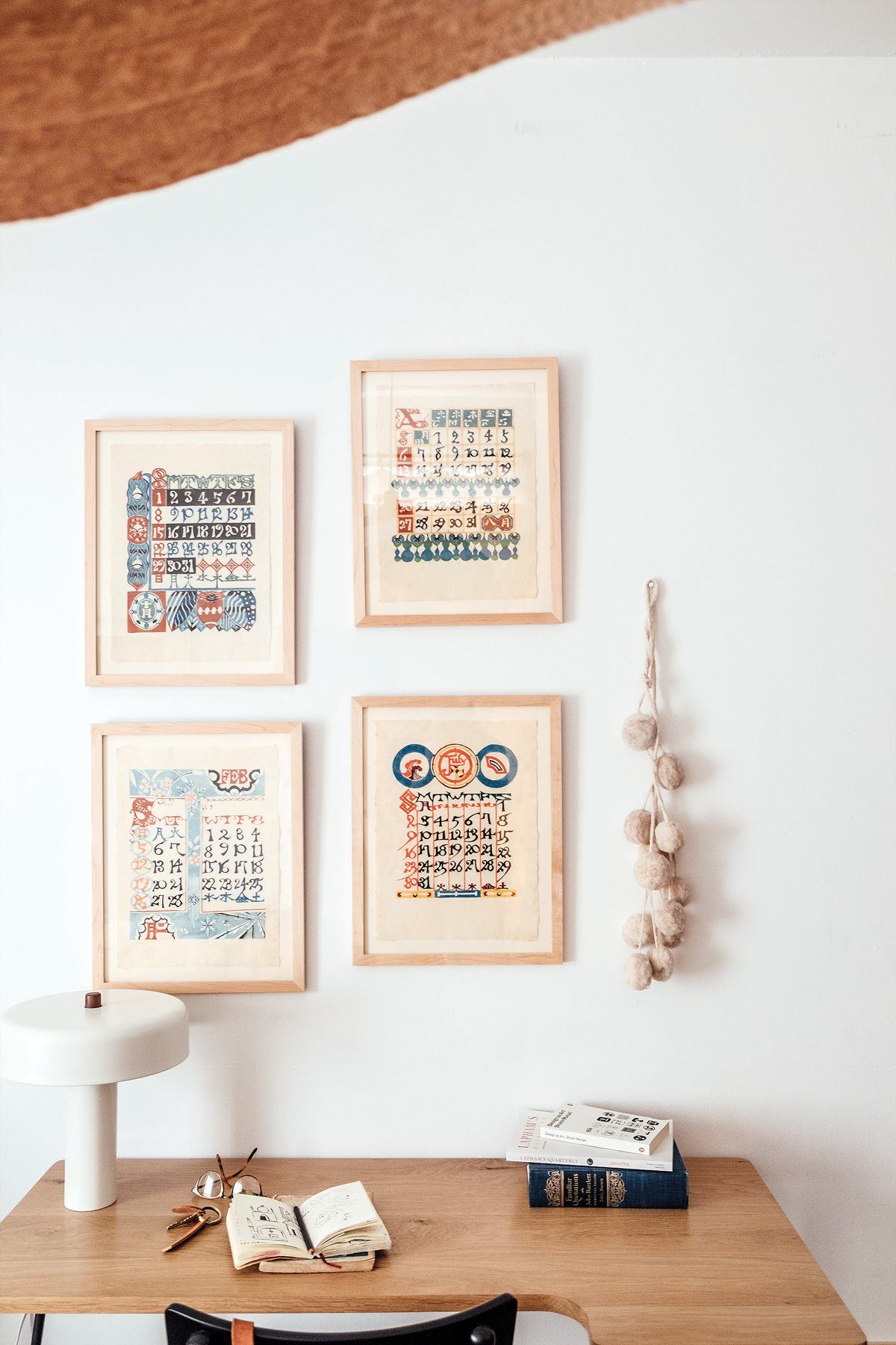 four framed prints hang on wall above desk